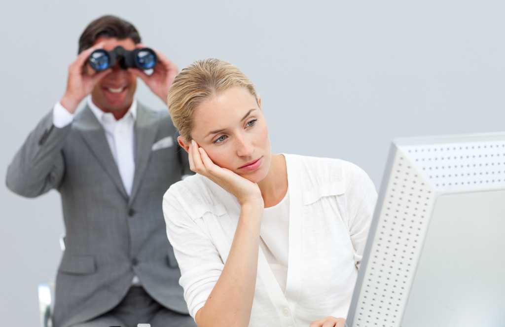 Manager using binoculars to see colleague's computer screen 125728197