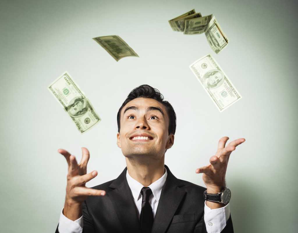 Man happily throwing money up in the air against green background