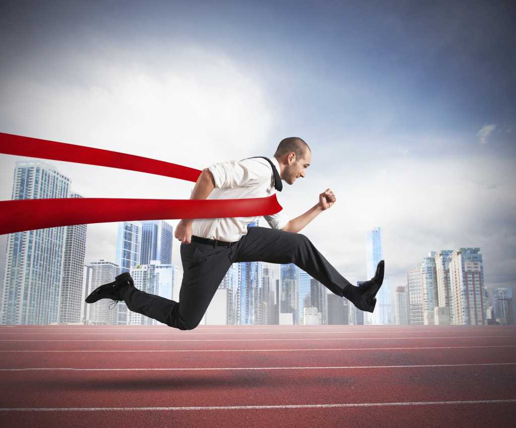Business man sprinting across finish line red tape speed