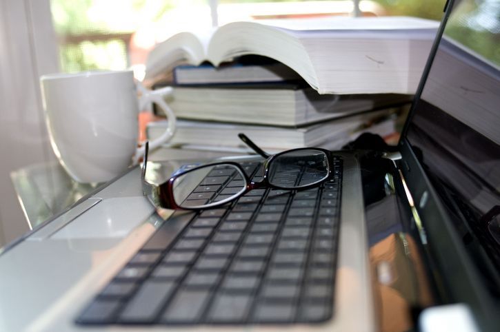 computer keyboard atop which a pair of reading glasses
