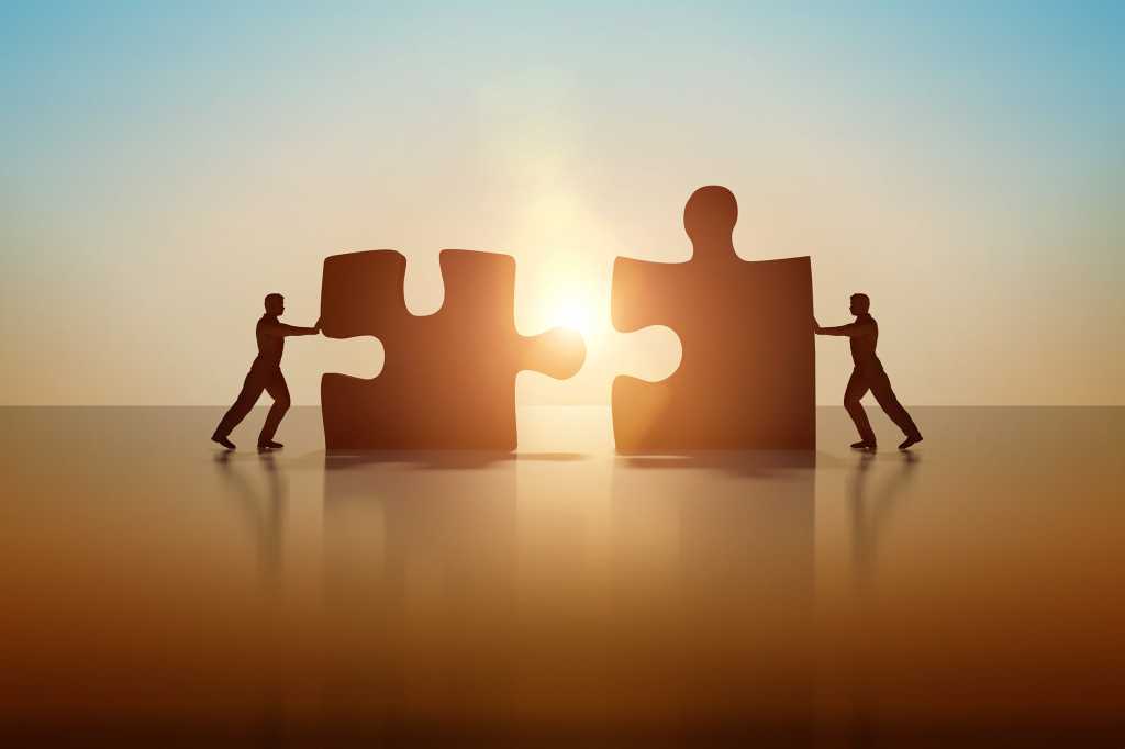 Two business people connecting and solving a puzzle.