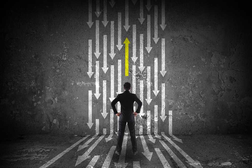 one yellow arrow moving opposite a stream of white arrows