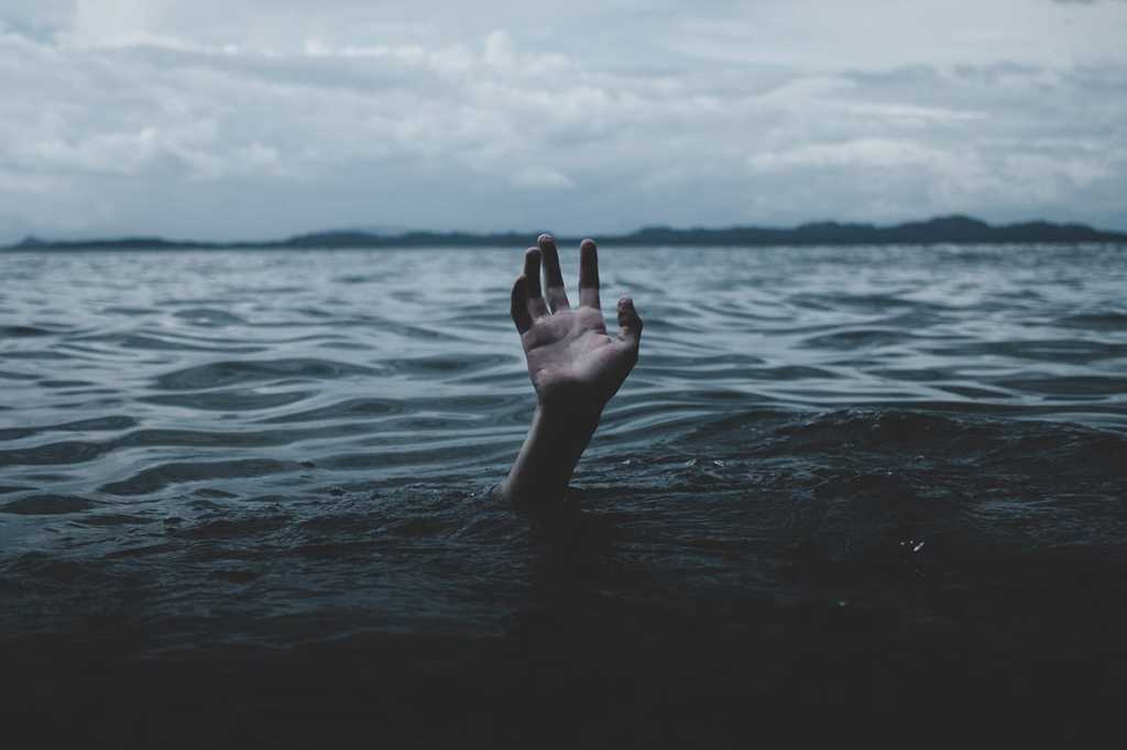 a hand rises from the ocean / someone in distress