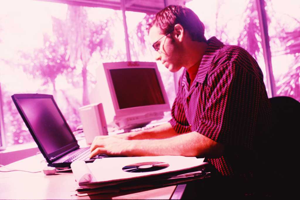 magental tinted image of worker at laptop computer 91910925