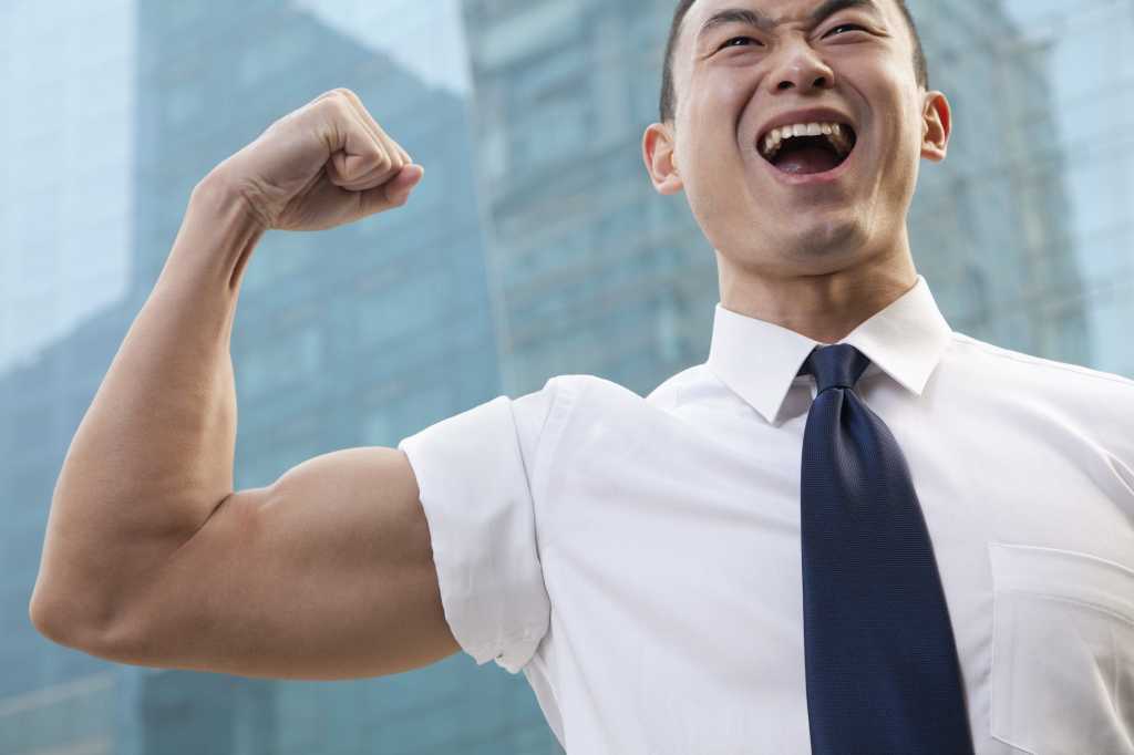portrait of young businessman flexing muscle outdoors 169277329