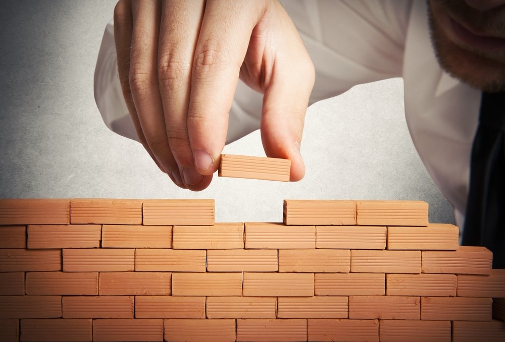 Man building miniature brick wall