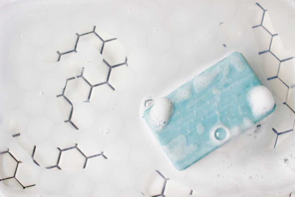 shutterstock 2125150196 blue bar of soap and foam on white tile background