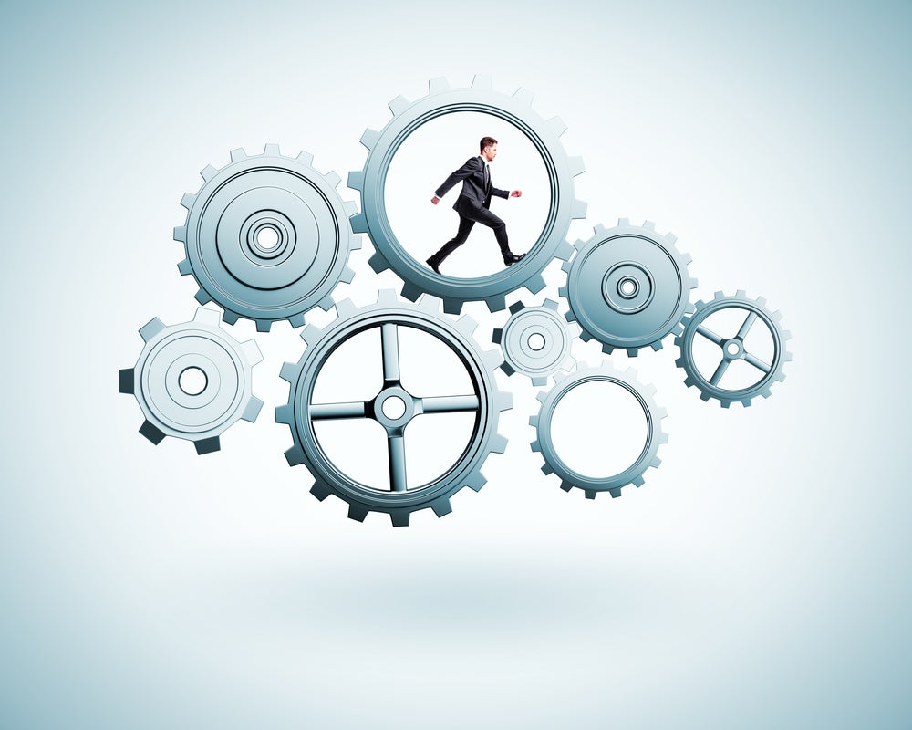 male executive walking within a cog among gears machinery