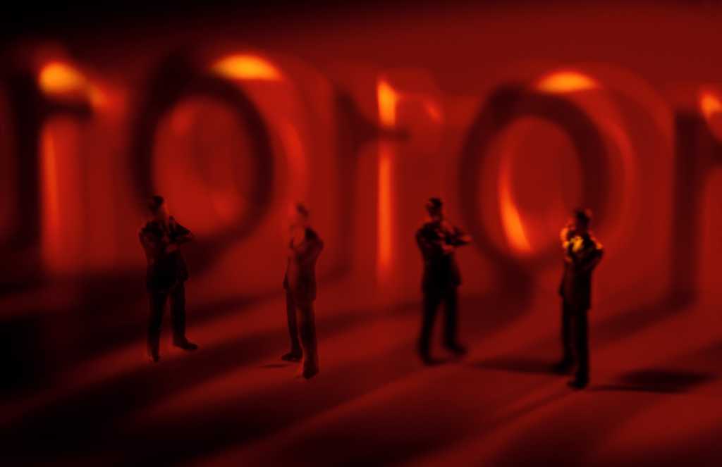 conceptual image with red background and miniature people standing in front of code