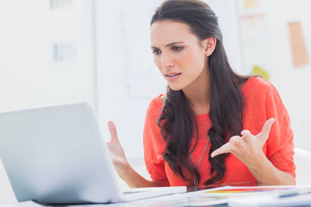 women in red shirt looking frustrated at laptop