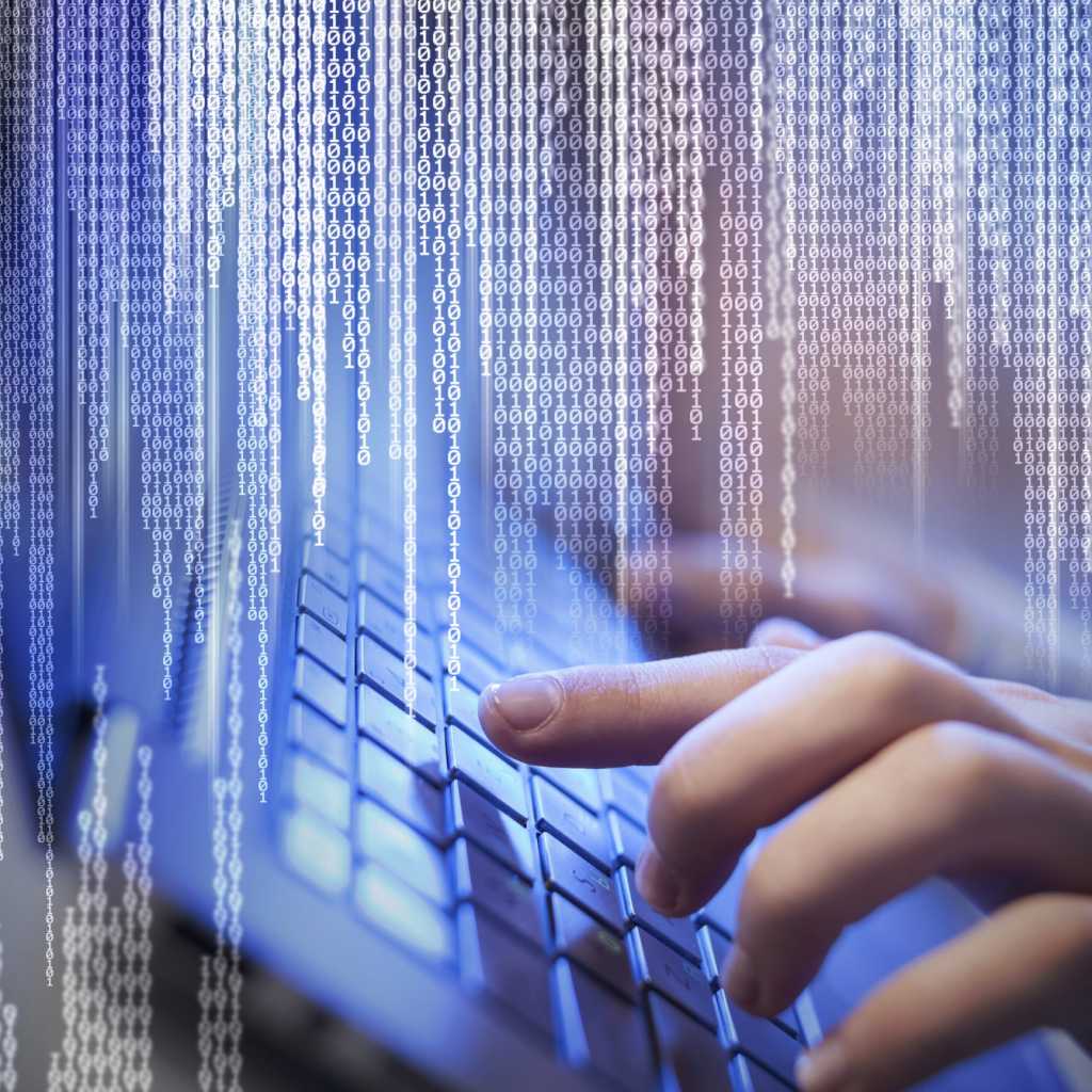 conceptual image of hand on keyboard with code raining down from above
