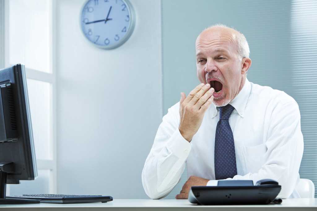 older executive sitting at laptop yawning