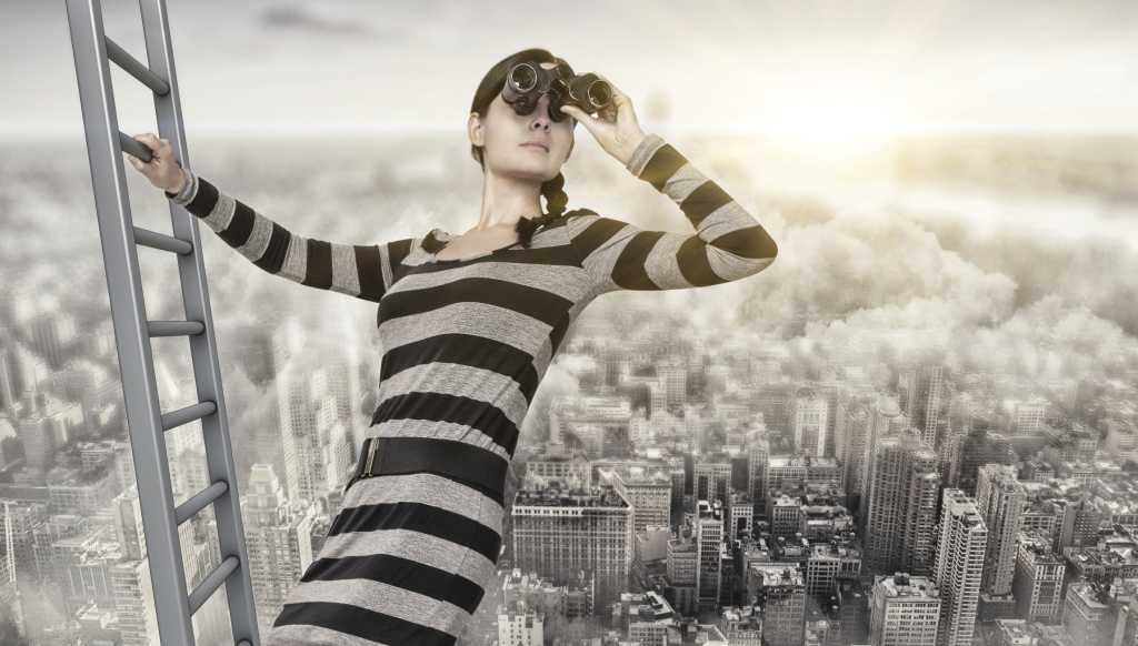 woman on ladder overlooking city looking through binoculars