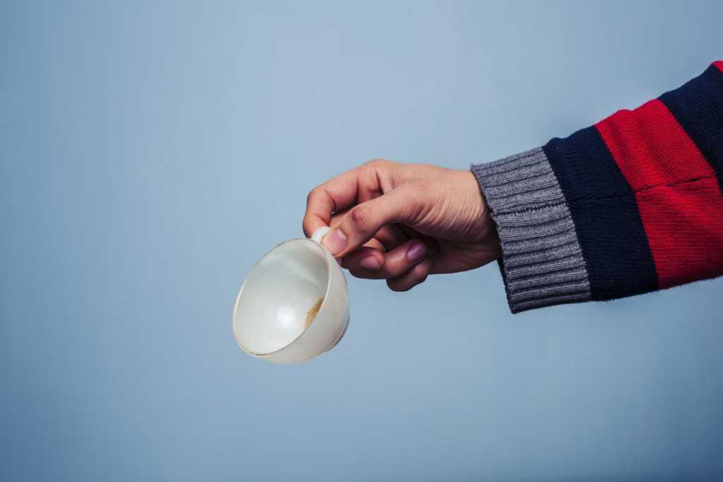 male arm holding empty coffee cup with striped sweater