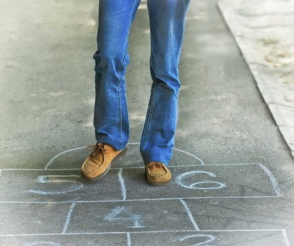 Man in blue jeans standing on hopscotch numbers