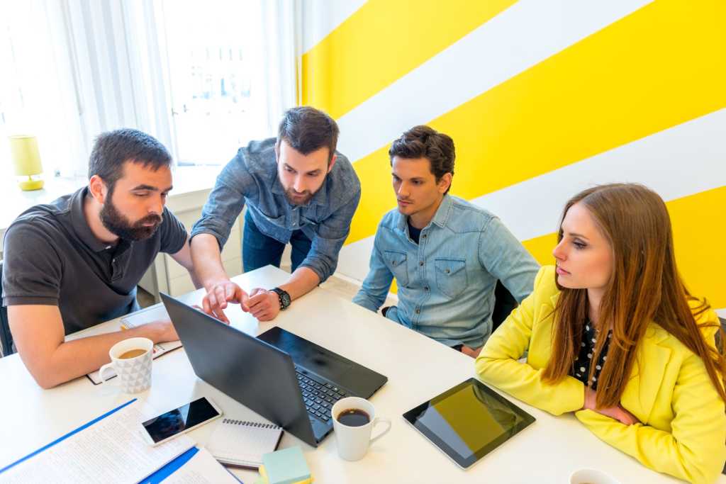 millenials casually grouped around computer and tablet collaborating on project