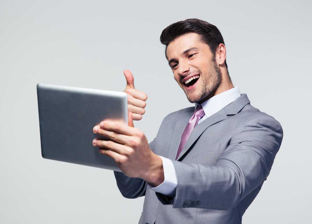 Handsome guy in gray suit holding hand thumbs up to tablet