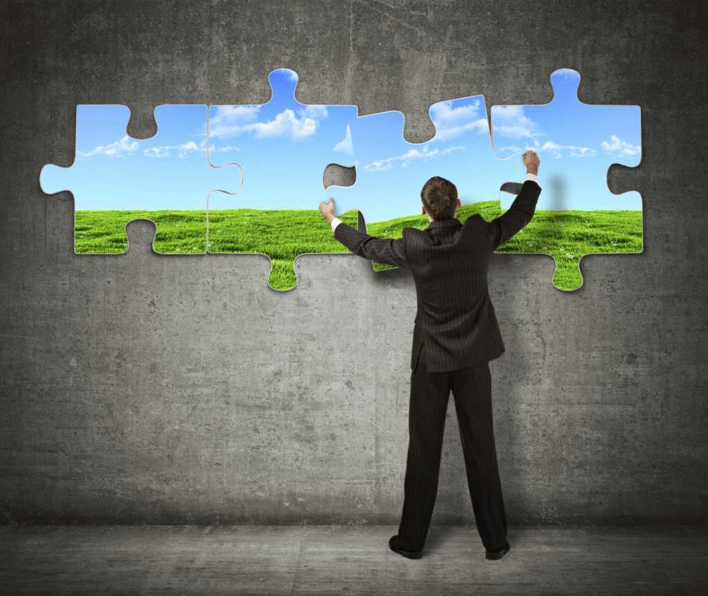 man in suit putting together giant puzzle pieces