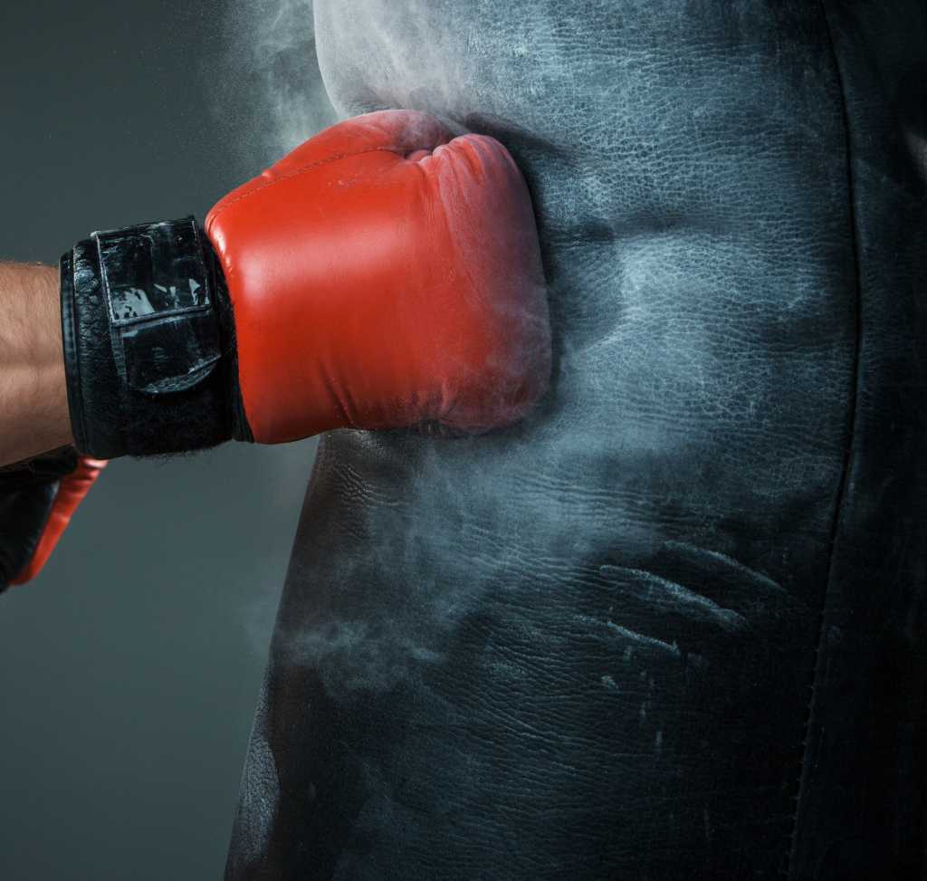 red boxing glove hitting punching bag