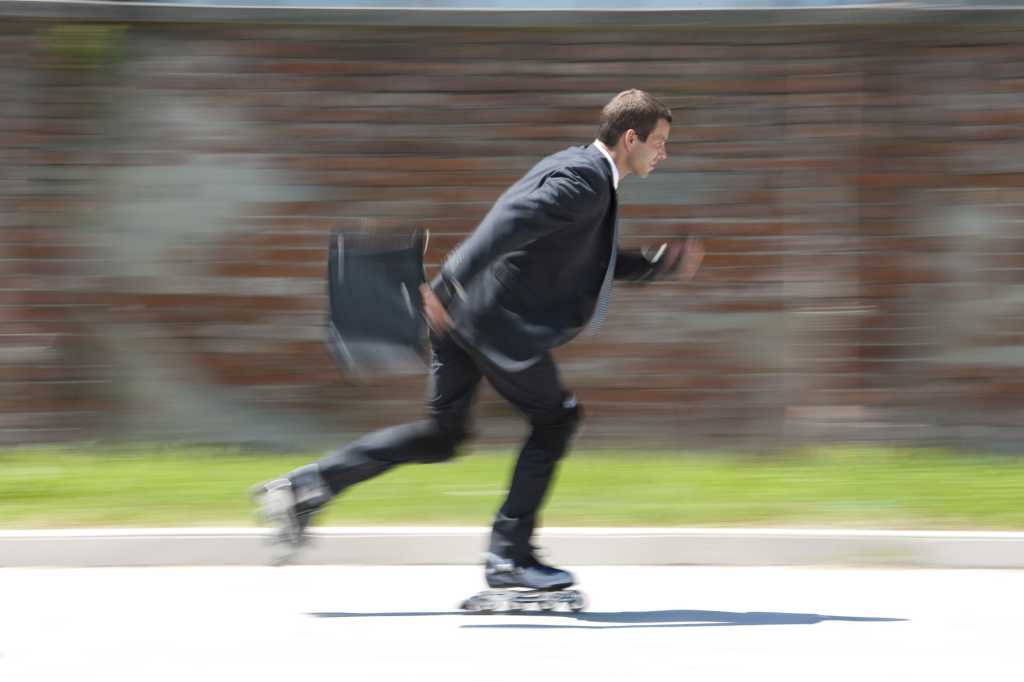 agile male executive on roller blades holding briefcase in motion