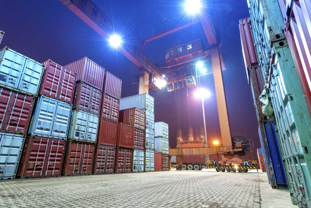 Cargo shipping containers stacked on dock at night