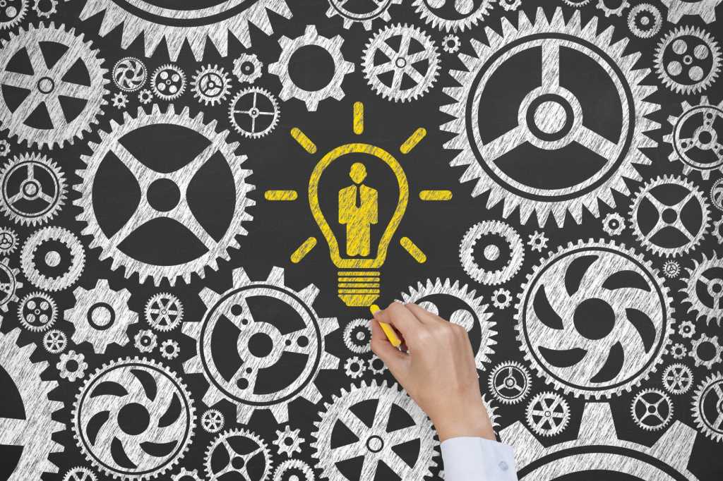 Hand drawing gears and lightbulb on chalkboard