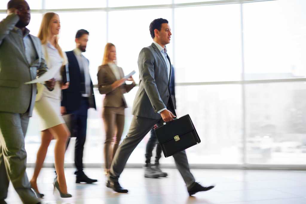 Group of executives marching down hallway with briefcase