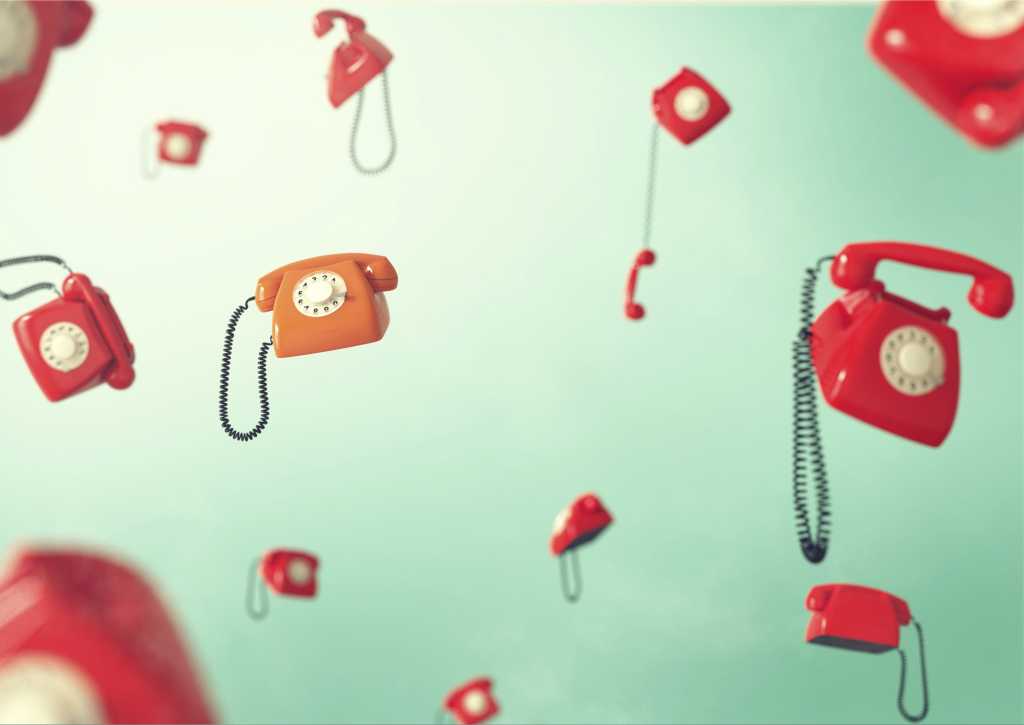 Flying red retro telephones on green background