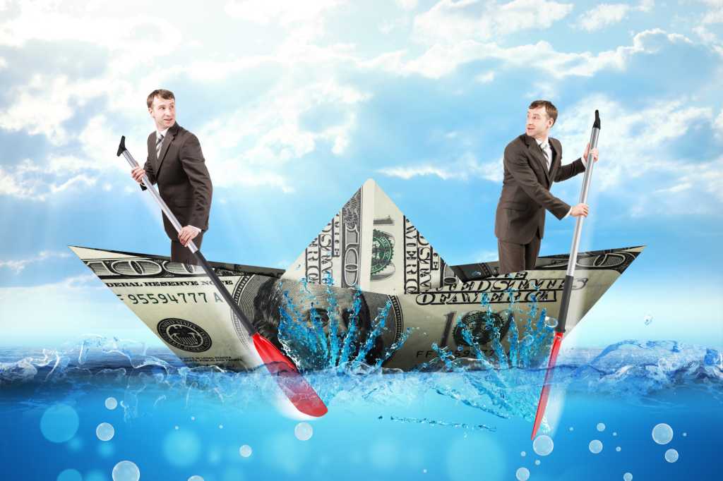 Two men paddling boat made of money against blue sky