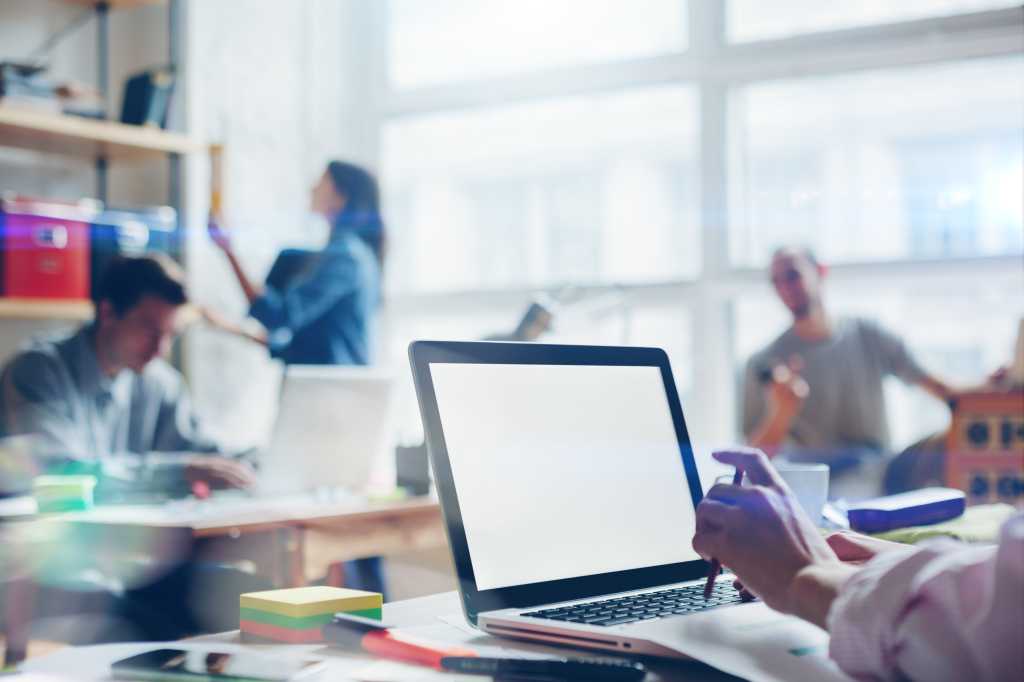 Group of people working in office with laptops