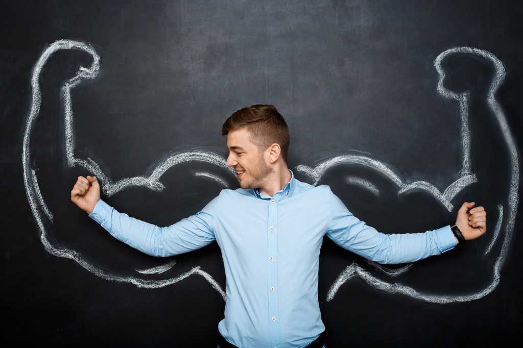 man flexing muscles in front of chalkboard