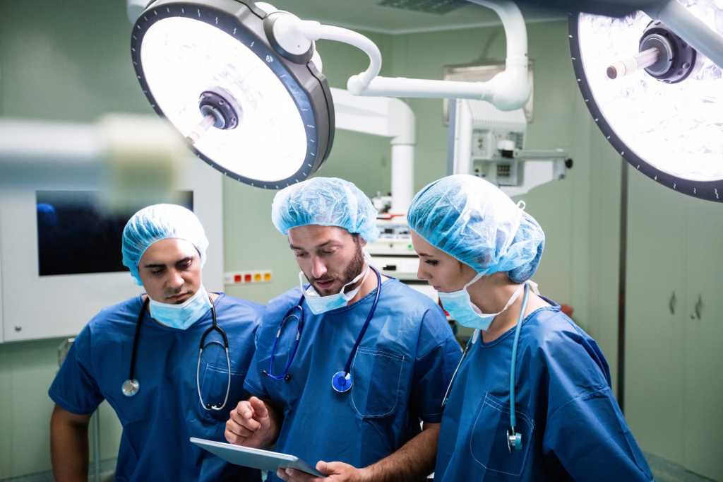 3 doctor surgeons in operating room on tablet