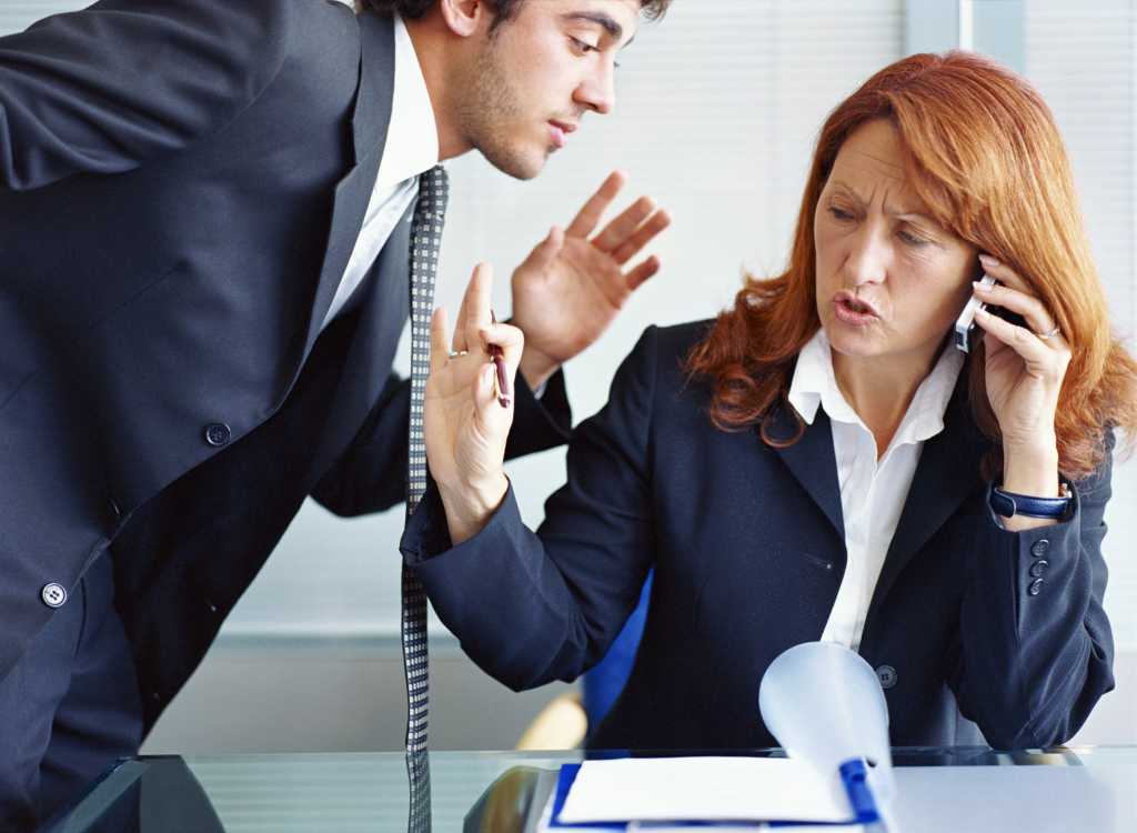 man in suit whispering to woman talking on the phone