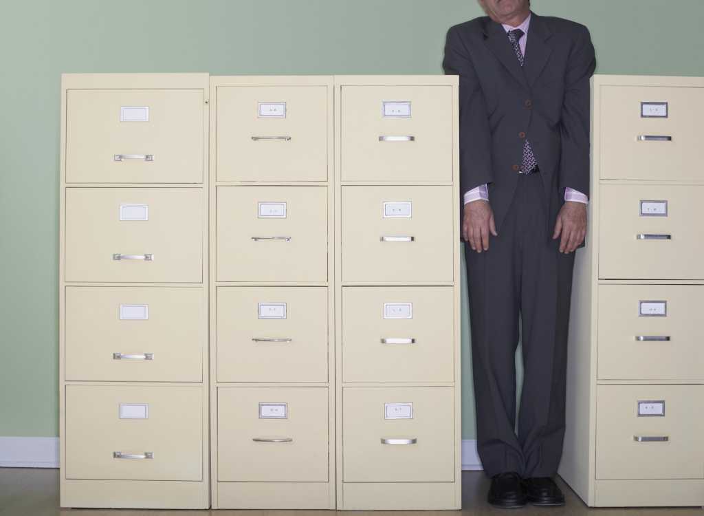 Man squeezed between file cabinets