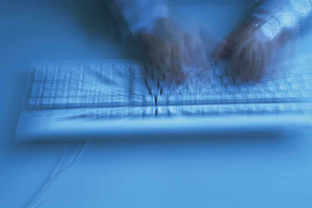 Blurry hands typing on computer keyboard