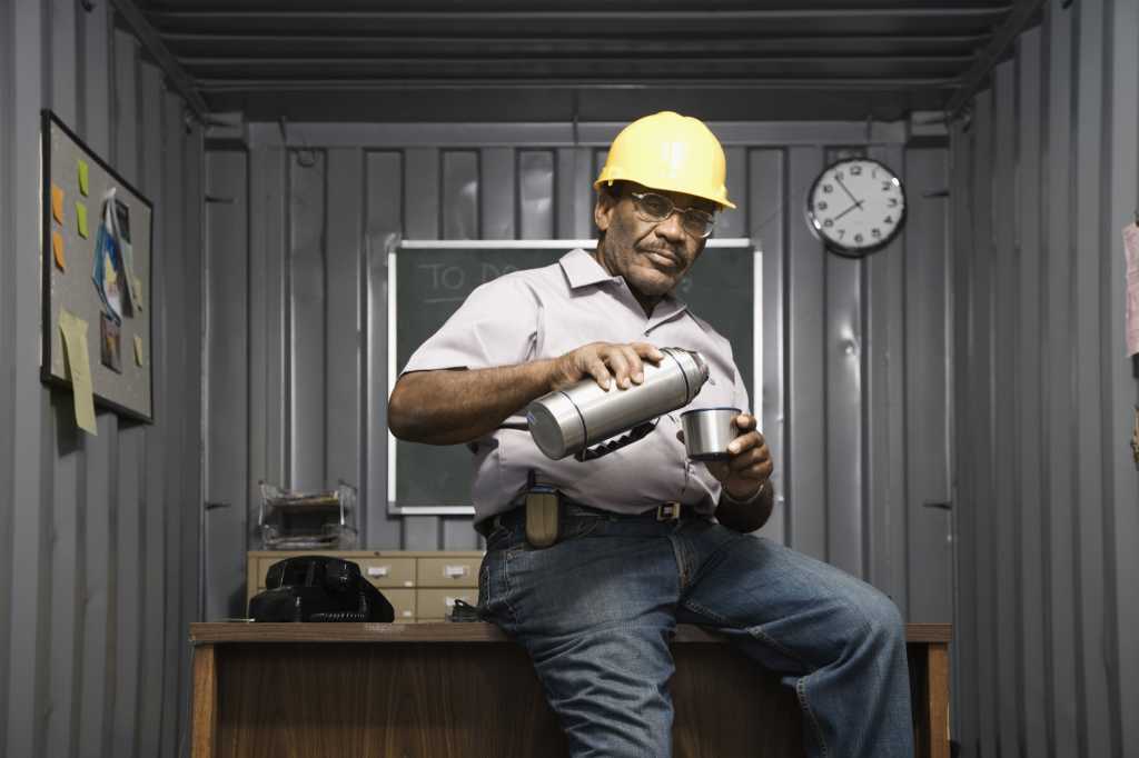construction guy in office with coffee sitting on desk