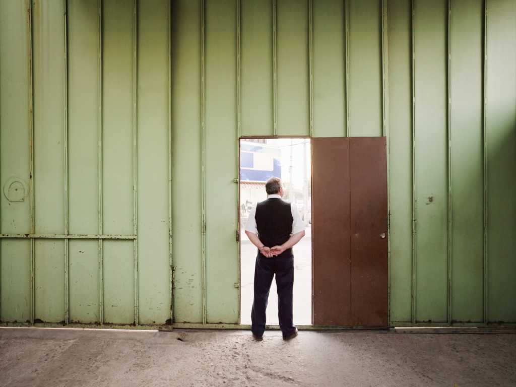 Man standing in open doorway in large empty green warehouse