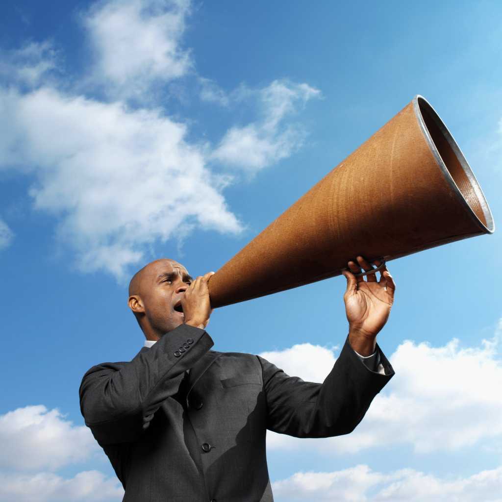 man holding large megaphone against blue cloudy sky