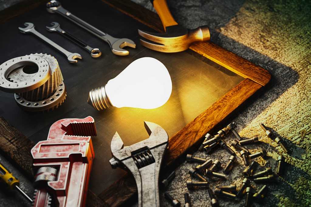 tools or toolkit surrounding a lightbulb on a chalkboard to build, develop or repair