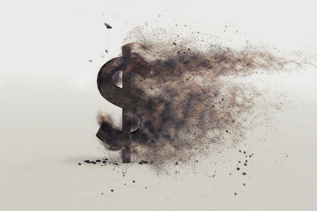 A U.S. dollar sign dissolves or bursts into particles.