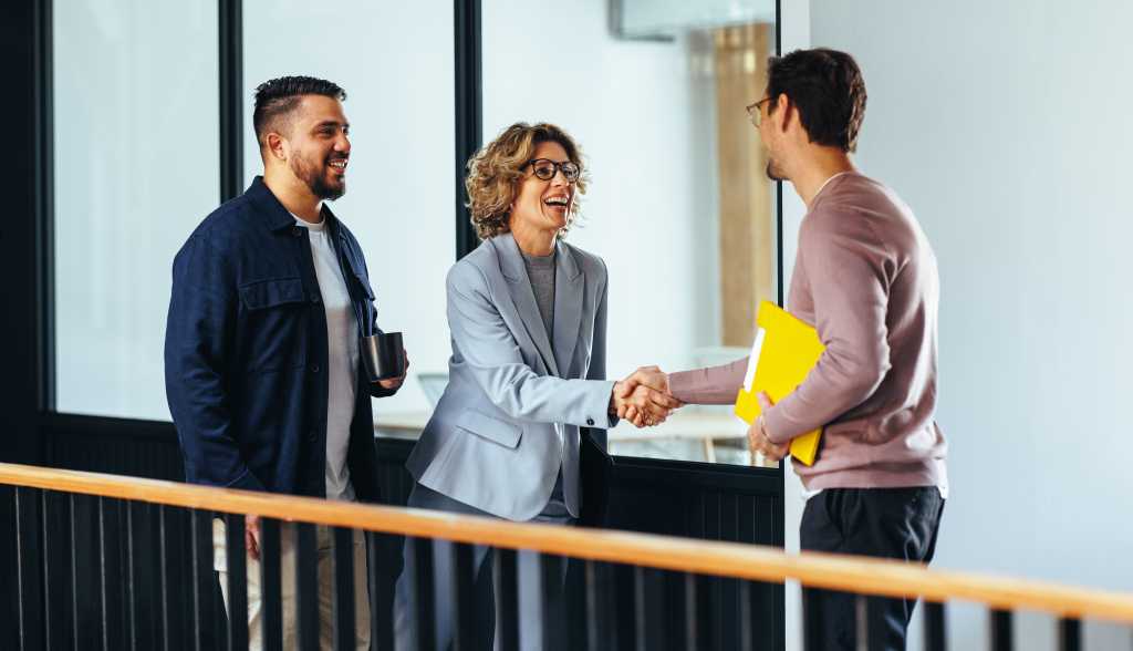 Professional woman shaking hands with a new employee in an office. Happy business woman hiring a job candidate. Business people forming a new partnership in a startup.