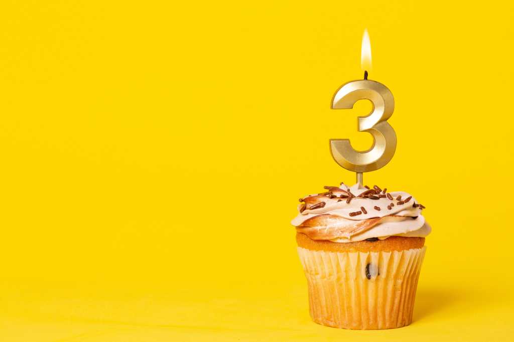Cupcake with a lit candle in the shape of the number 3.