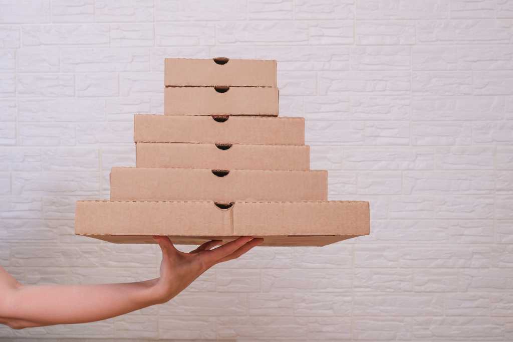 An outstretched hand balances stacked, small boxes. Containers theme.