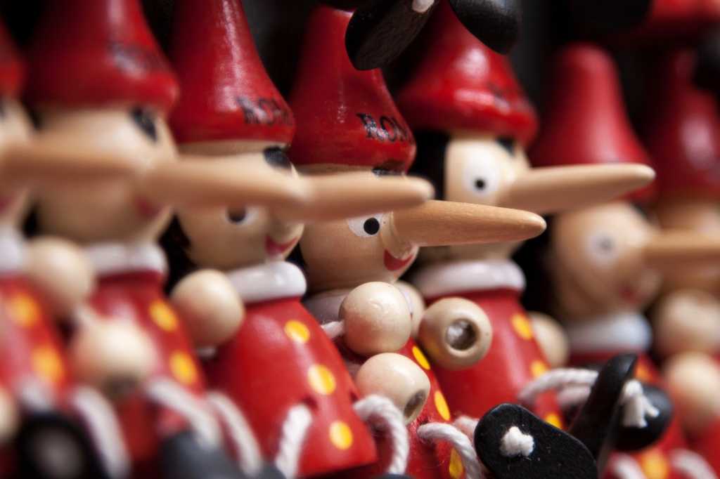 close up view of wooden puppets Pinochios with long noses red hats white collars red shirts with yellow buttons