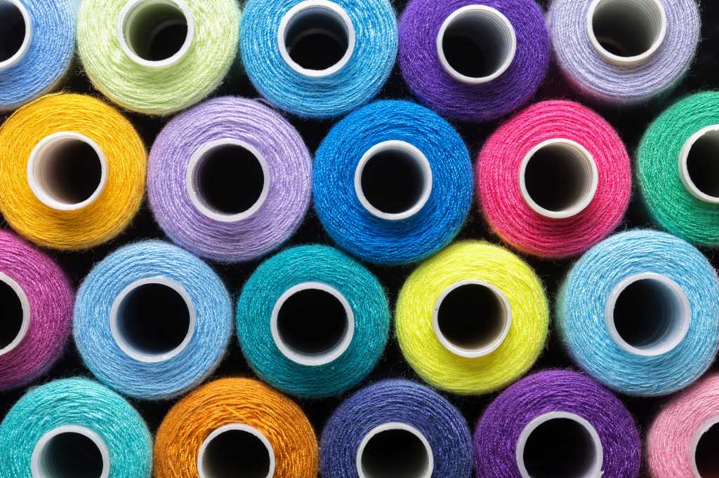 sewing thread in different colors pink blue green red yellow purple