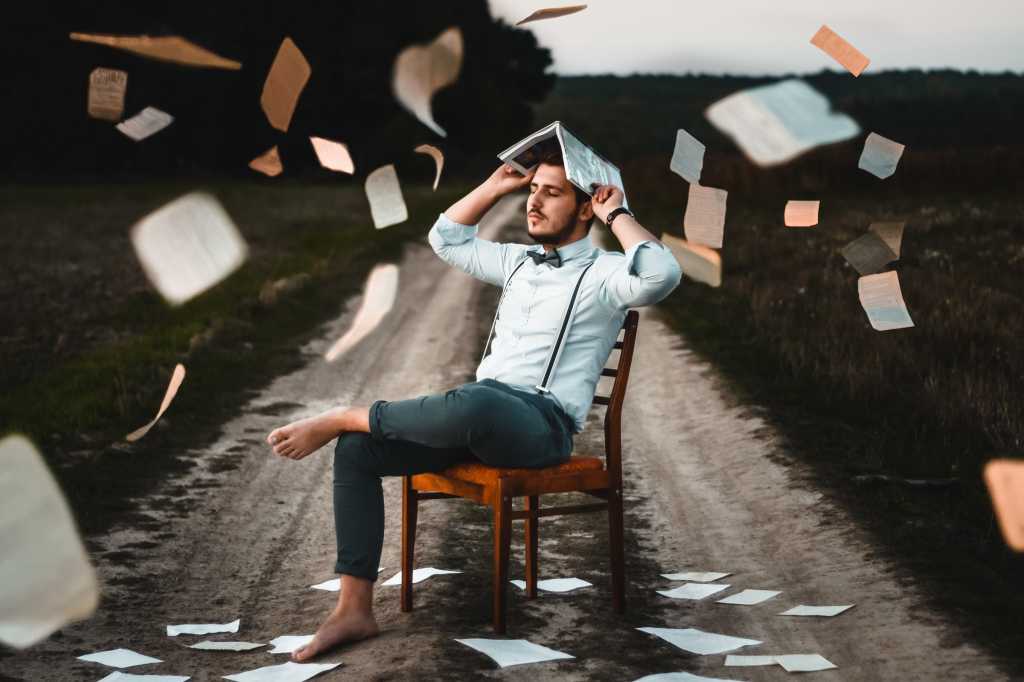man in chair flying papers learning thinking student graduate school study dirt road by photo by dm