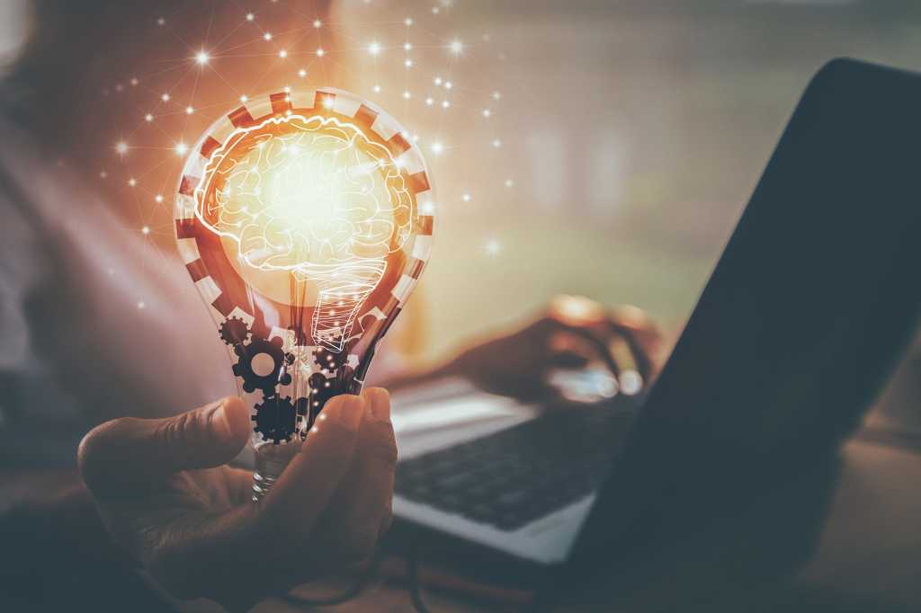 A light bulb with gears and a network of sparks that form the shape of a virtual brain.