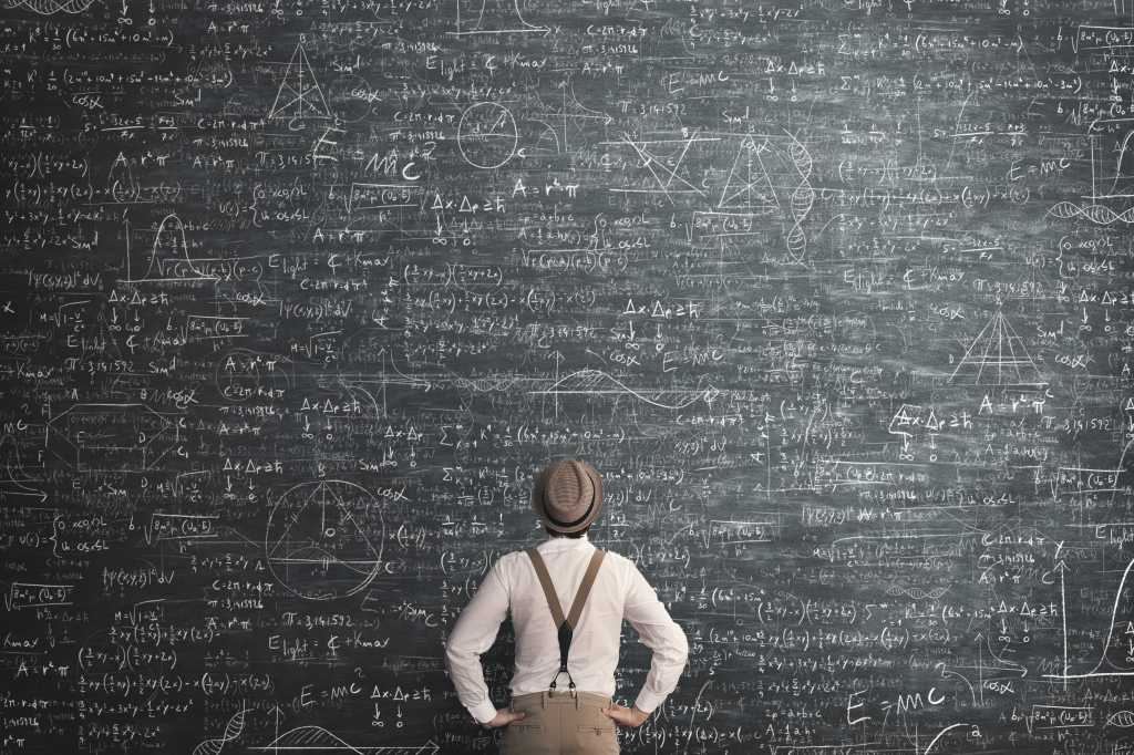 Man contemplates a large blackboard full of mathematical equations. Complexity.