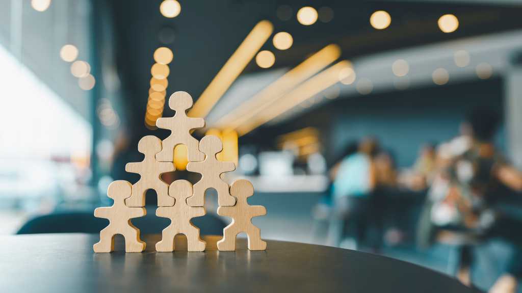 Human-figure cutouts arranged in a standing pyramid formation. Teamwork.