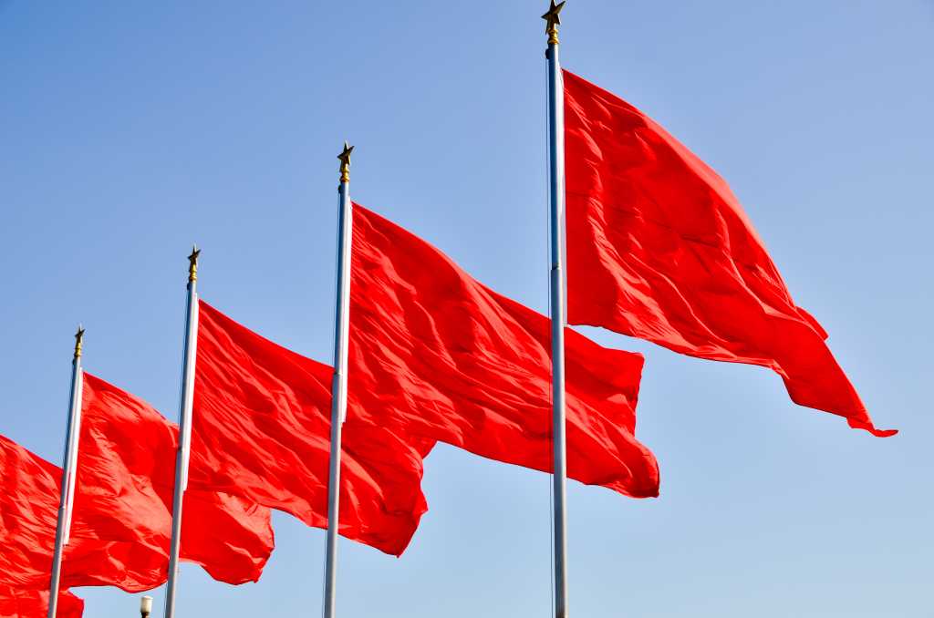 Five 5 red flags fluttering in the wind against a clear blue sky